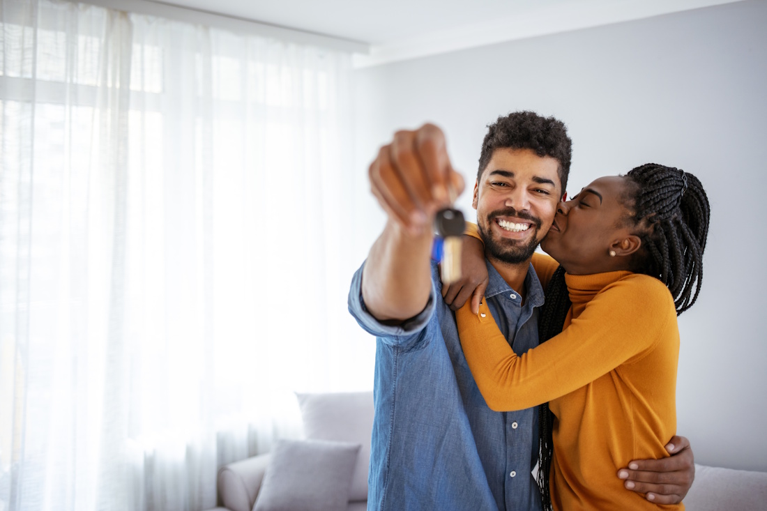 Woman is kissing her husband who's holding up their new house keys