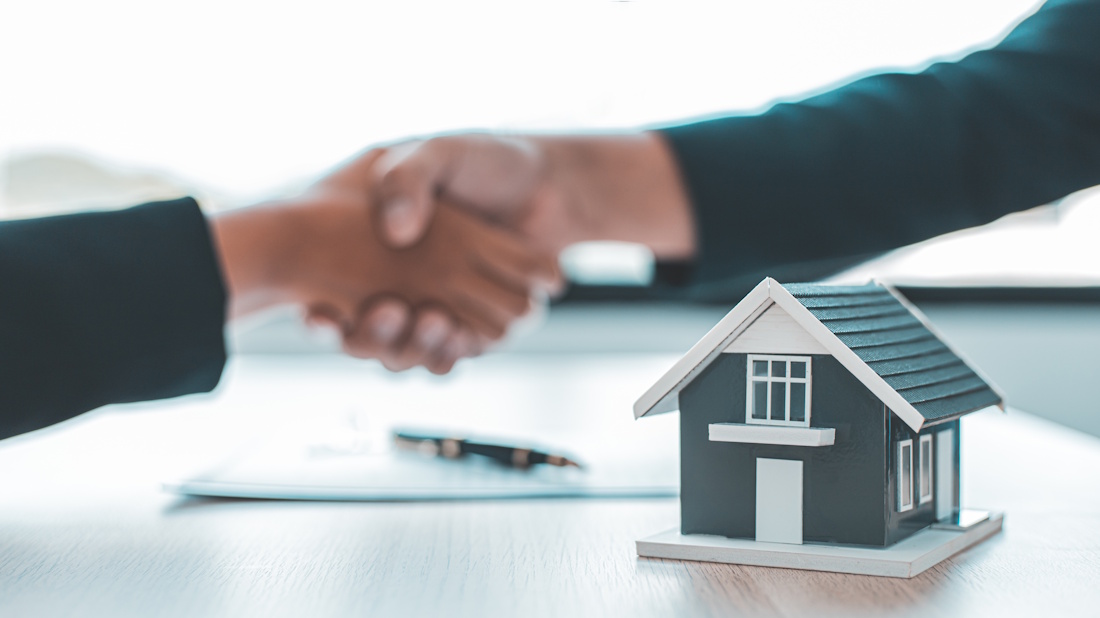 A small house and two people shaking hands