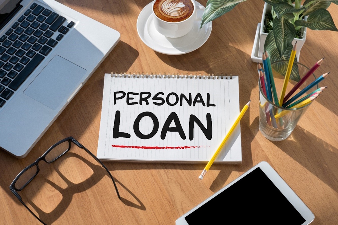 A desk with a notepad that says Personal Loan