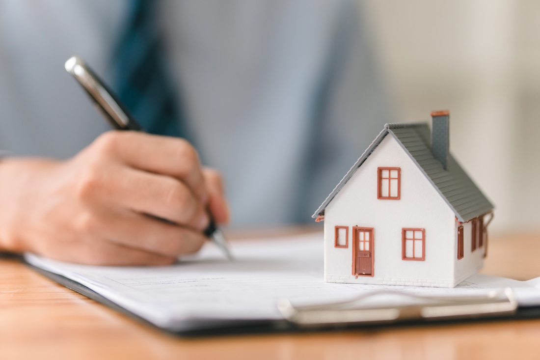 A small house and a person writing on some documents
