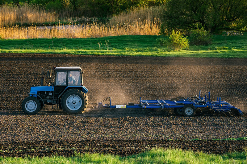 Blue tractor plowing a field