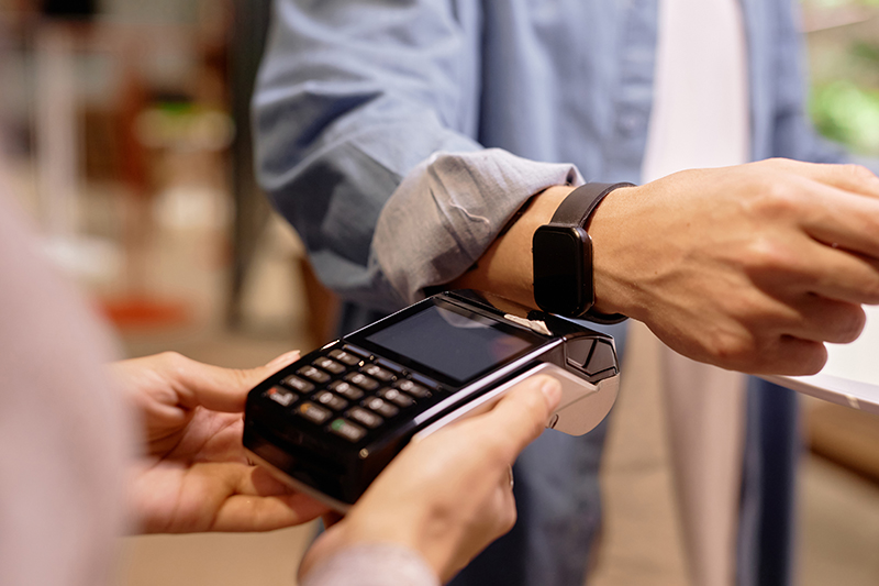 Man making a payment at a point-of-sale device with his apple or smartwatch device.