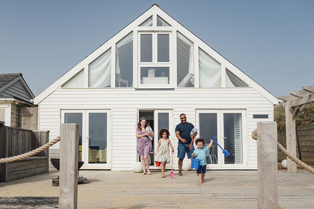 Family walking across deck with kids holding beach toys