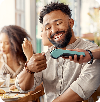 young man using debit card to pay bill at restaurant tap to pay