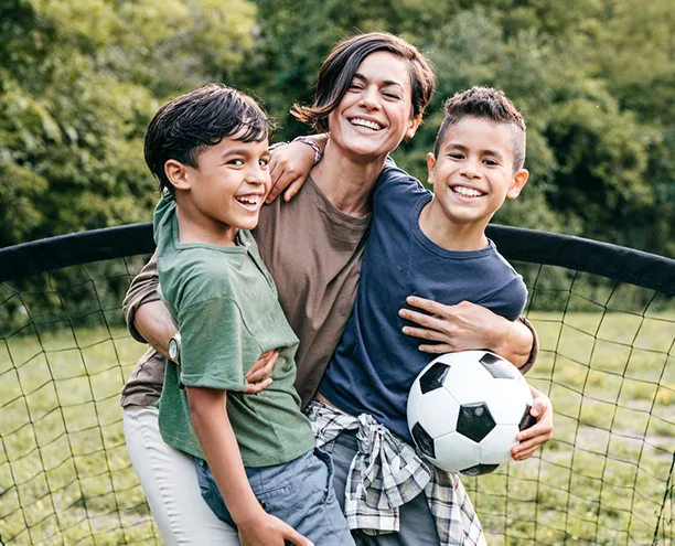 mother with her two sons playing soccer outdoors