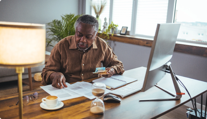 A mature man sitting at his computer desk reviewing documents