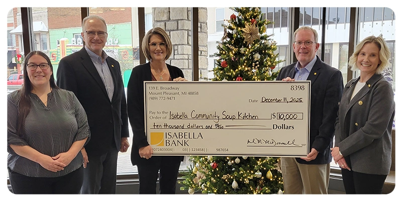 five people standing behind a large check with a donation to the Isabella Community Soup Kitchen