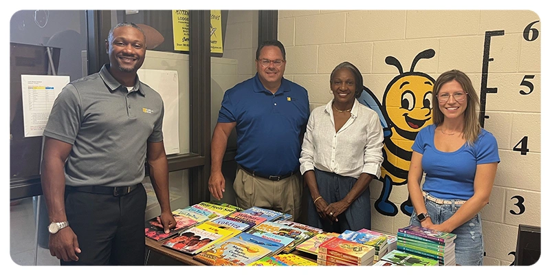four people standing behind a table with books at Stone Elementary in Saginaw