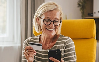 clickswitch mature woman using debit card and phone