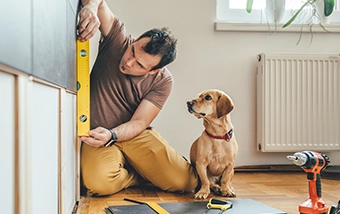 A man doing a renovation with his dog watching