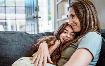 mother cuddling with daughter on couch
