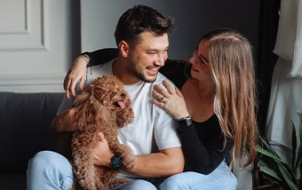 Young couple sitting on the couch with their dog