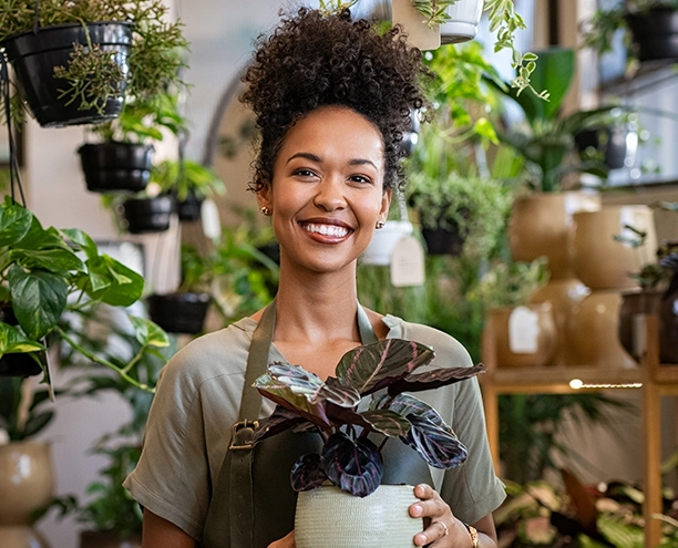 Woman smiling holding a plant in a plant shop