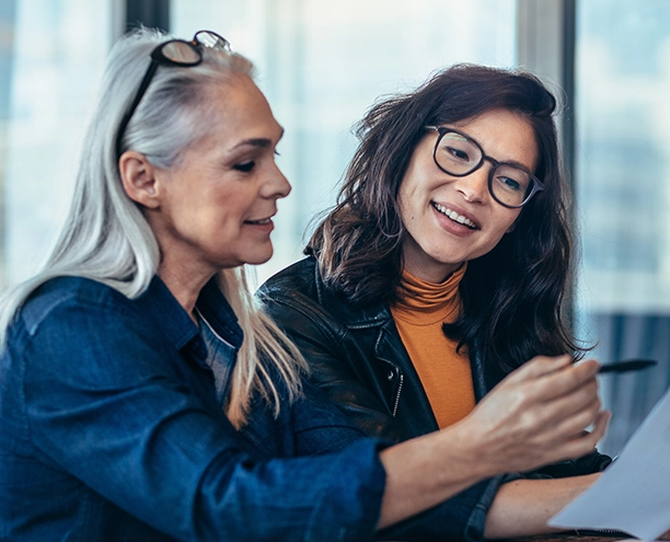 Two women smiling, reviewing a business report