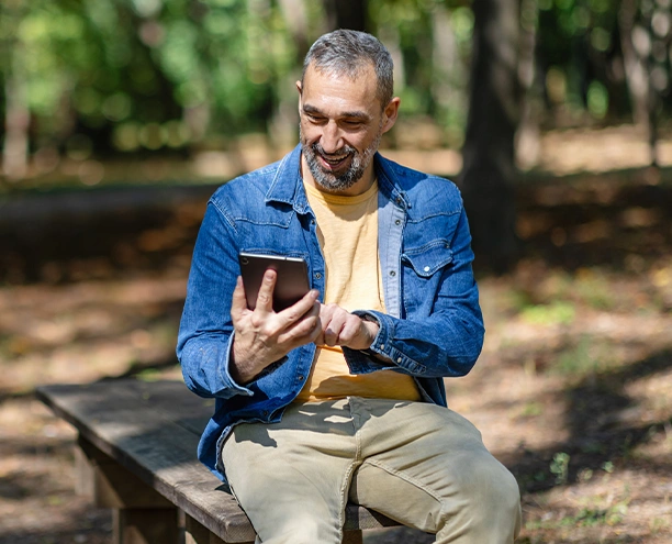 mature man holding phone in a park