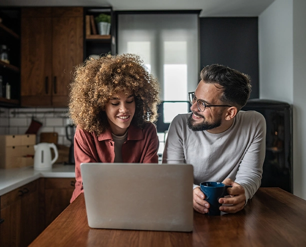 couple at kitchen table going over finances at computer