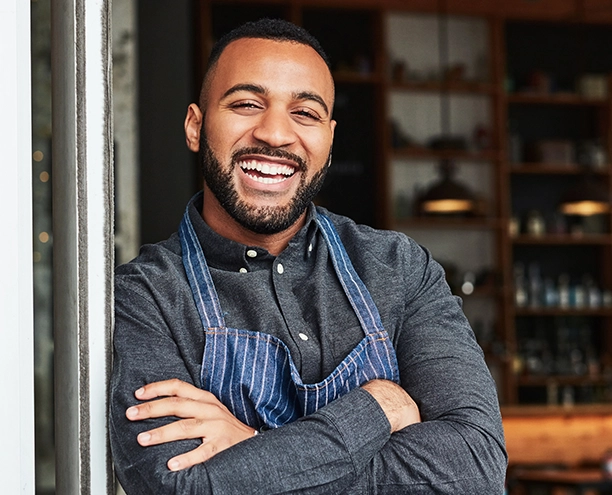 A small business owner smiling with his arms crossed