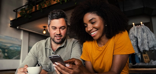 couple of adults checking their phone while sitting at a cafe