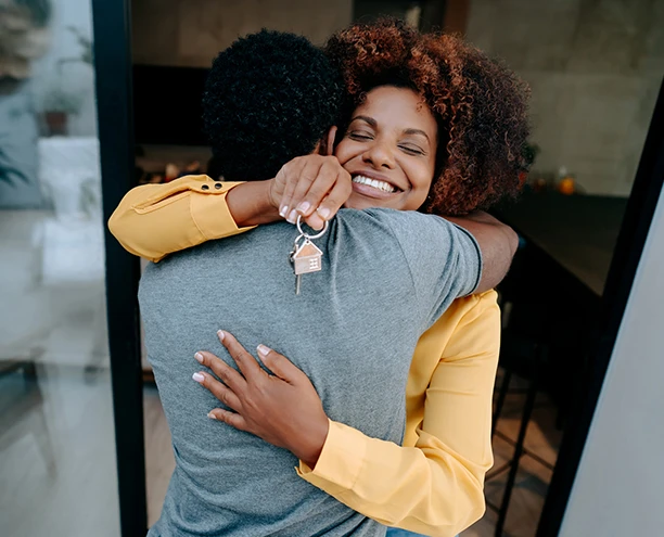 couple hugging after purchasing their new home holding keys