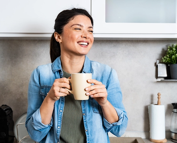 Woman smiling holding a coffee mug