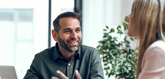 a man sitting and smiling at a woman talking
