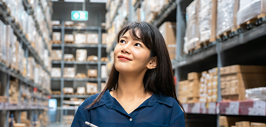 Smiling business owner walking through aisles of inventory