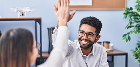 A man with glasses high-fiving a fellow employee