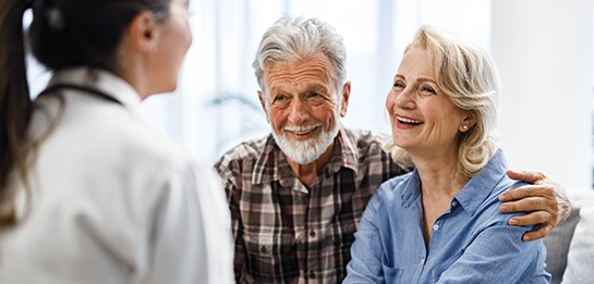 Older couple talking to a doctor, smiling