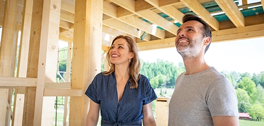Couple smiling waling into a newly built house frame