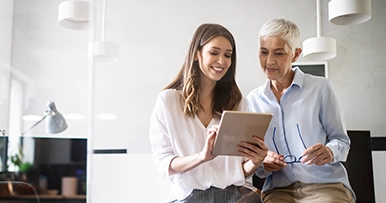 Two women discussing finances and looking at an ipad