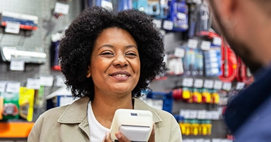 Store owner smiling, holding a handheld POS terminal
