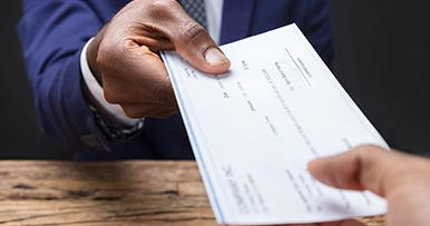 Close up of a check being handed to another person