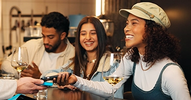 group of friends paying for a night out at the bar with phone digital wallet