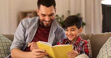 father and son reading a book together in the living room