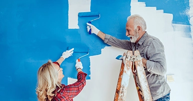 A senior couple painting a wall blue