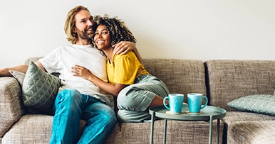A happy couple hugging on their couch