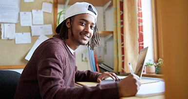 young male student studying in his dorm room at university